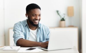 Smiling african american guy in earphones studying foreign language online